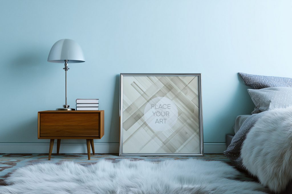 Square silver wall art frame mockup on a white shaggy rug in a blue vintage bedroom with a mid-century nightstand and a mushroom lamp.