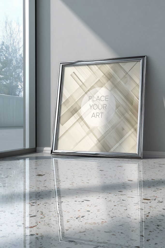 wall-art-frame-mockup-atomic-era-retro-terrazzo-chrome-vertical.jpg Vertical wall art frame mockup with a polished chrome finish leaning against a grey wall on a reflective terrazzo floor next to a large window.