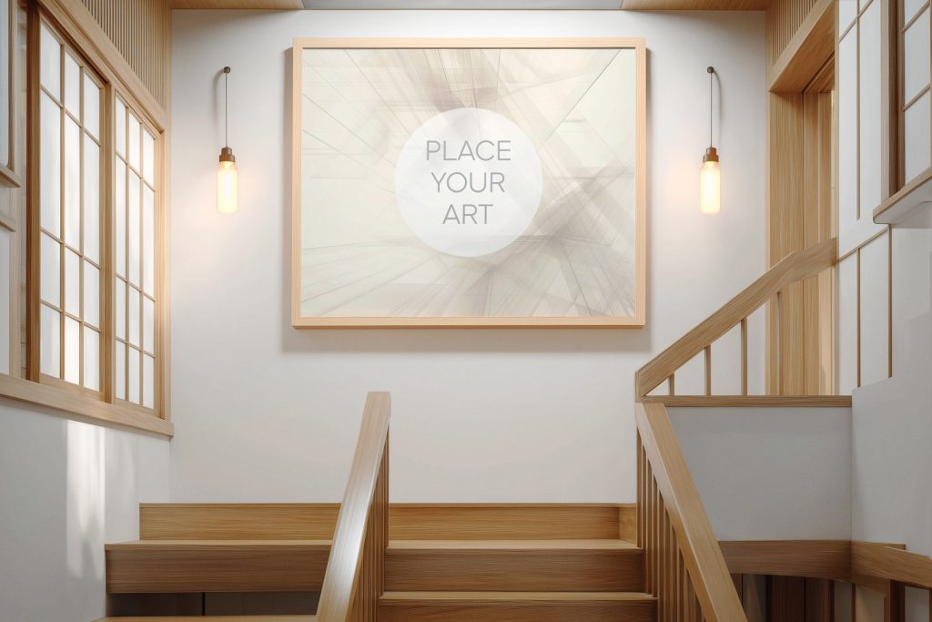 Large horizontal light wood frame mockup on a white wall above a wooden staircase, flanked by two warm pendant lights in a Japandi interior.