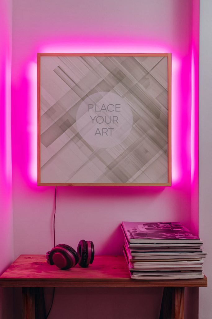 Lo-Fi aesthetic square frame mockup with magenta neon backlight, vintage headphones, and a stack of magazines on a wooden table.