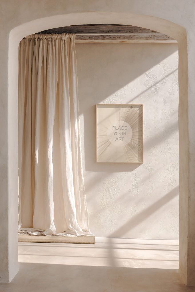 A vertical art frame mockup hanging on a textured wall viewed through a Mediterranean-style arched doorway, featuring soft sunlight and linen curtains.