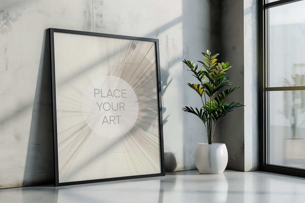 Large vertical wall art mockup leaning against a raw concrete corner wall next to a white spherical ceramic pot with a green plant by a tall studio window.