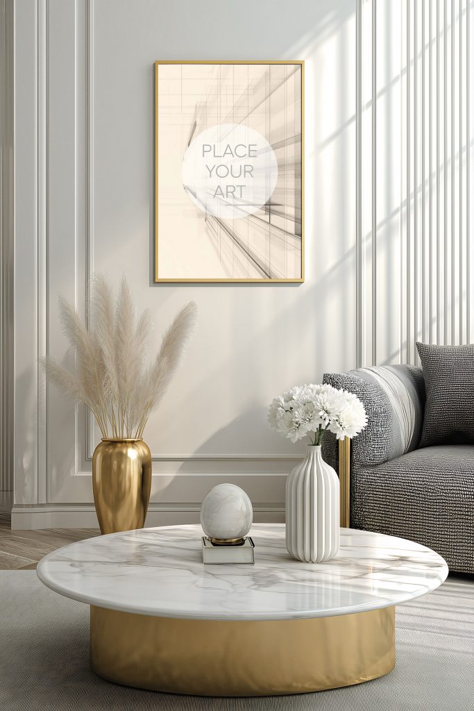 vertical-gold-frame-mockup-white-marble-table-bright-art-deco-living-room.jpg Vertical gold frame mockup hanging on a white paneled wall above a round marble coffee table with gold accents and pampas grass.